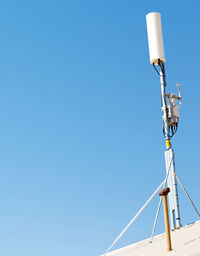 Low angle view of telephone pole against clear blue sky