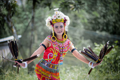 Portrait of young woman standing against trees