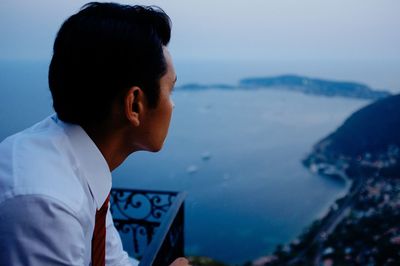 Portrait of young man looking at mountains against sky