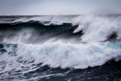 Waves splashing in sea against sky