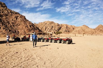 People at desert against sky