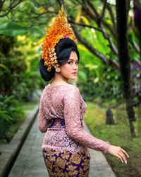 Portrait of young woman standing against trees