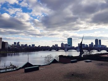 Buildings by river against sky in city