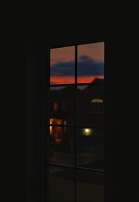 Silhouette building seen through window at night
