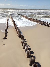 Panoramic view of wooden posts on beach against sky