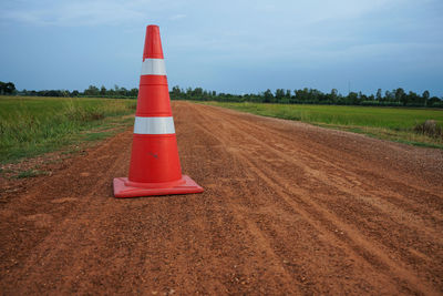 Road sign on field against sky