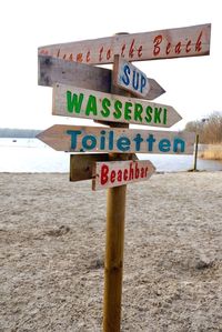 Close-up of road sign on beach against sky