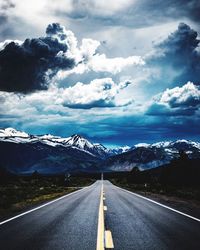 Road by mountains against sky