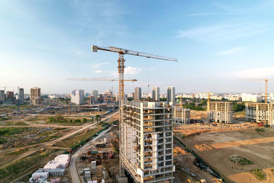 Cranes at construction site against buildings in city