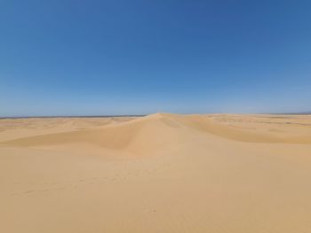 Scenic view of desert against clear blue sky