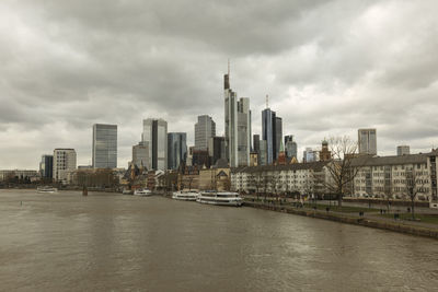 View of buildings at waterfront against cloudy sky