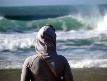 Rear view of woman in gray hooded shirt at beach