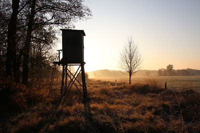 Silhouette hut on field against sky during sunset