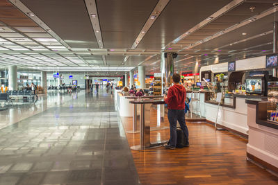 Rear view of people standing in illuminated corridor