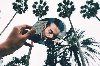Man holding mirror against sky