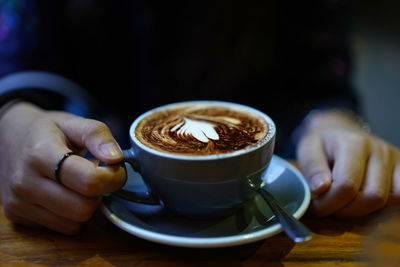 Midsection of person holding coffee cup on table