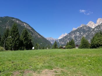 Scenic view of field and mountains against clear blue sky