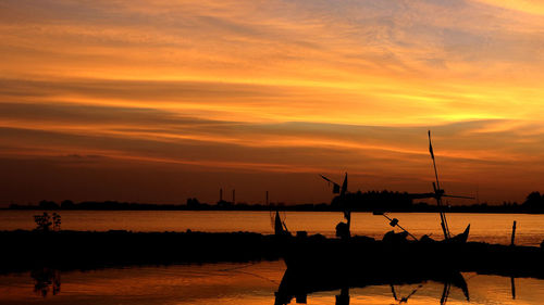 Silhouette people on sea against sky during sunset