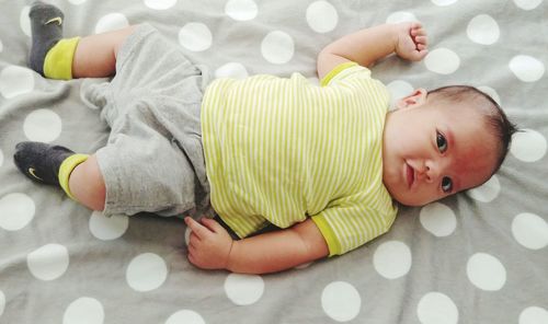 Directly above portrait of baby boy lying on bed at home