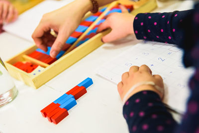 High angle view of baby hand holding paper at table