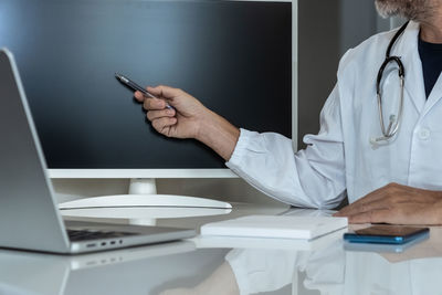 Midsection of man using mobile phone at table