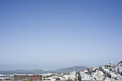 Cityscape and sea against clear blue sky