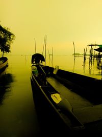 Sailboats moored on lake against sky during sunset