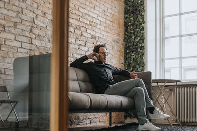 Businessman talking on mobile phone while sitting on sofa in office