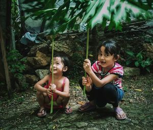 Portrait of cute girls holding stems on field