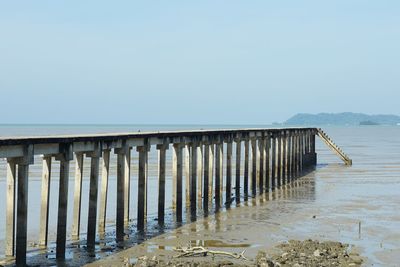 Pier on beach against clear sky