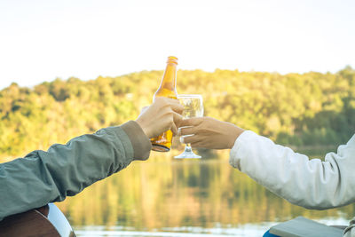 Close-up of man holding drink on field against sky