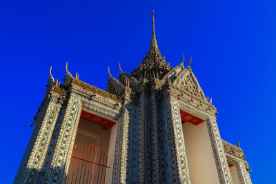 Low angle view of temple against building against clear blue sky