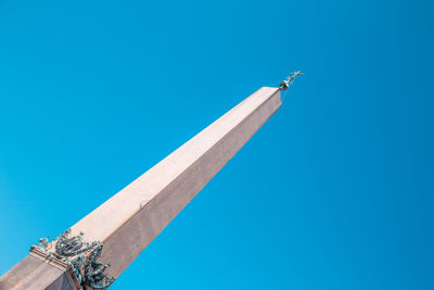 Low angle view of cross against building against clear blue sky