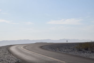 Road leading towards mountain against sky