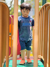 Portrait of cute boy standing on railing