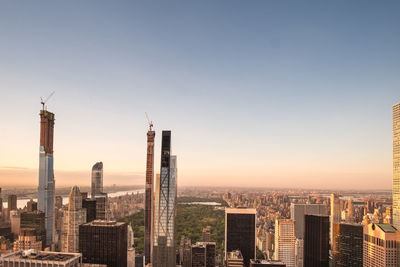 Modern buildings in city against clear sky during sunset