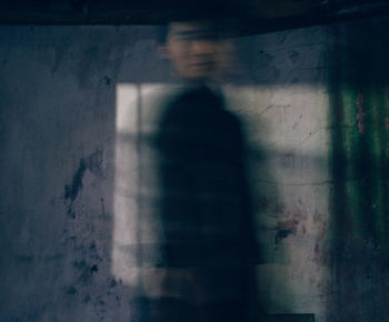 Blurred image of man standing by wall