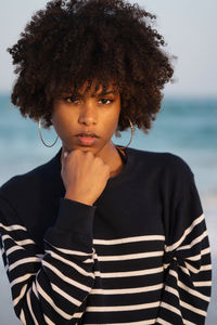 Young black woman standing by the sea wearing striped jumper