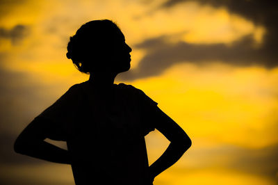 Silhouette boy standing against sky during sunset