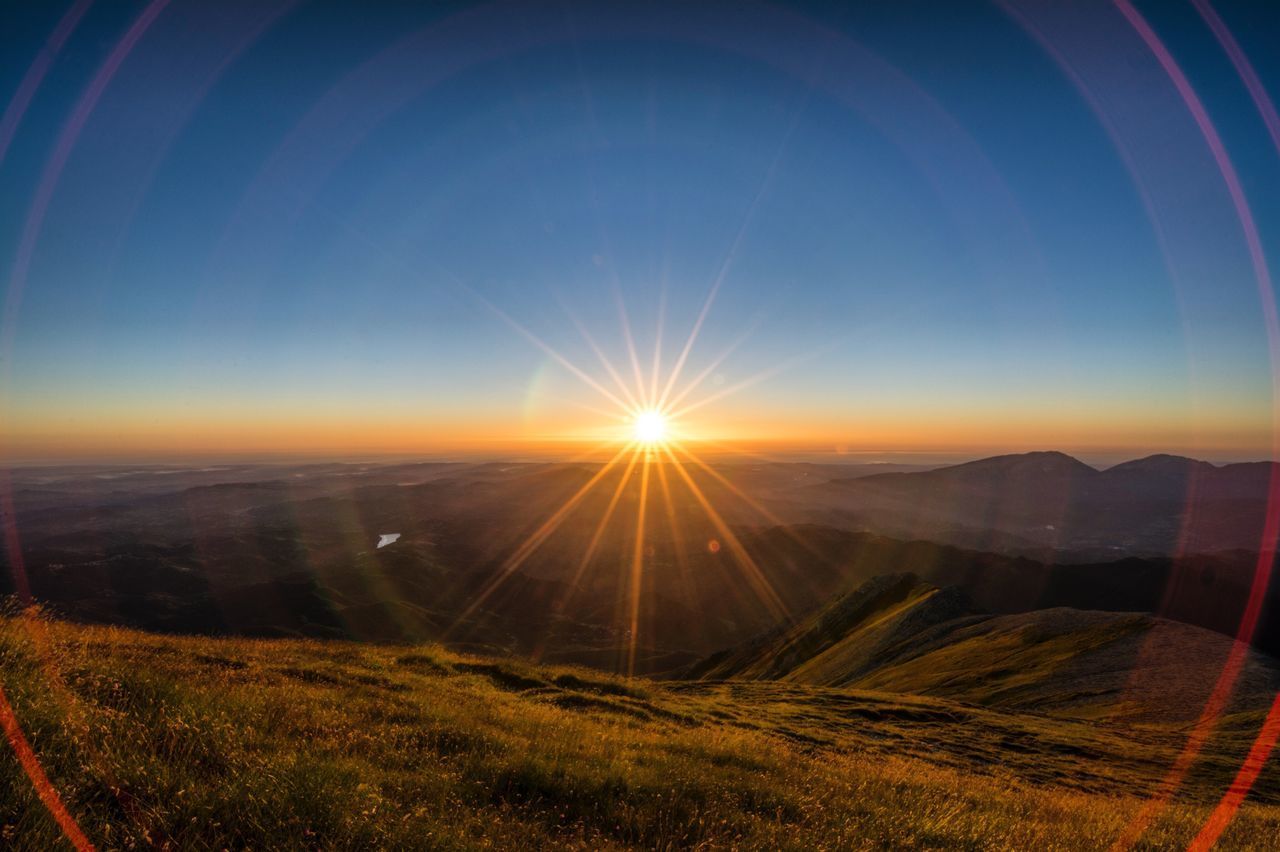 SCENIC VIEW OF FIELD AGAINST BRIGHT SUN AT SUNSET