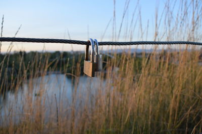 Close-up of chain hanging on fence against sky
