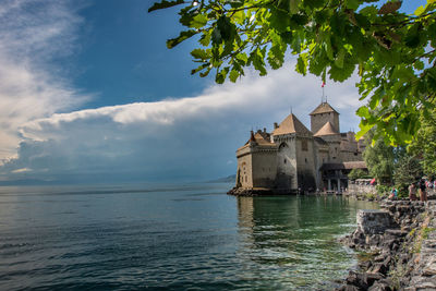 Building by sea against cloudy sky