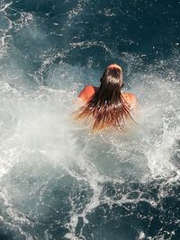 Rear view of woman splashing water