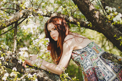 Portrait of young woman with flowers on tree