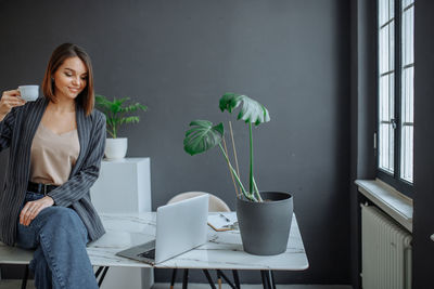 Portrait of young woman using laptop at home