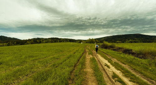 Panorama of a person with backpack hiking in meadow field in countryside on a way to lubon wielki