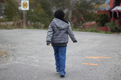 Rear view of man walking on road