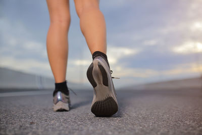 Female sport runner getting ready for jogging outdoors on  the city road.