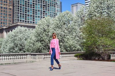 Full length portrait of woman standing against trees in city