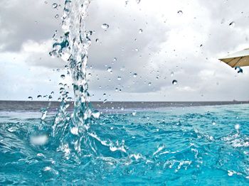 Close-up of water splashing in swimming pool against sky